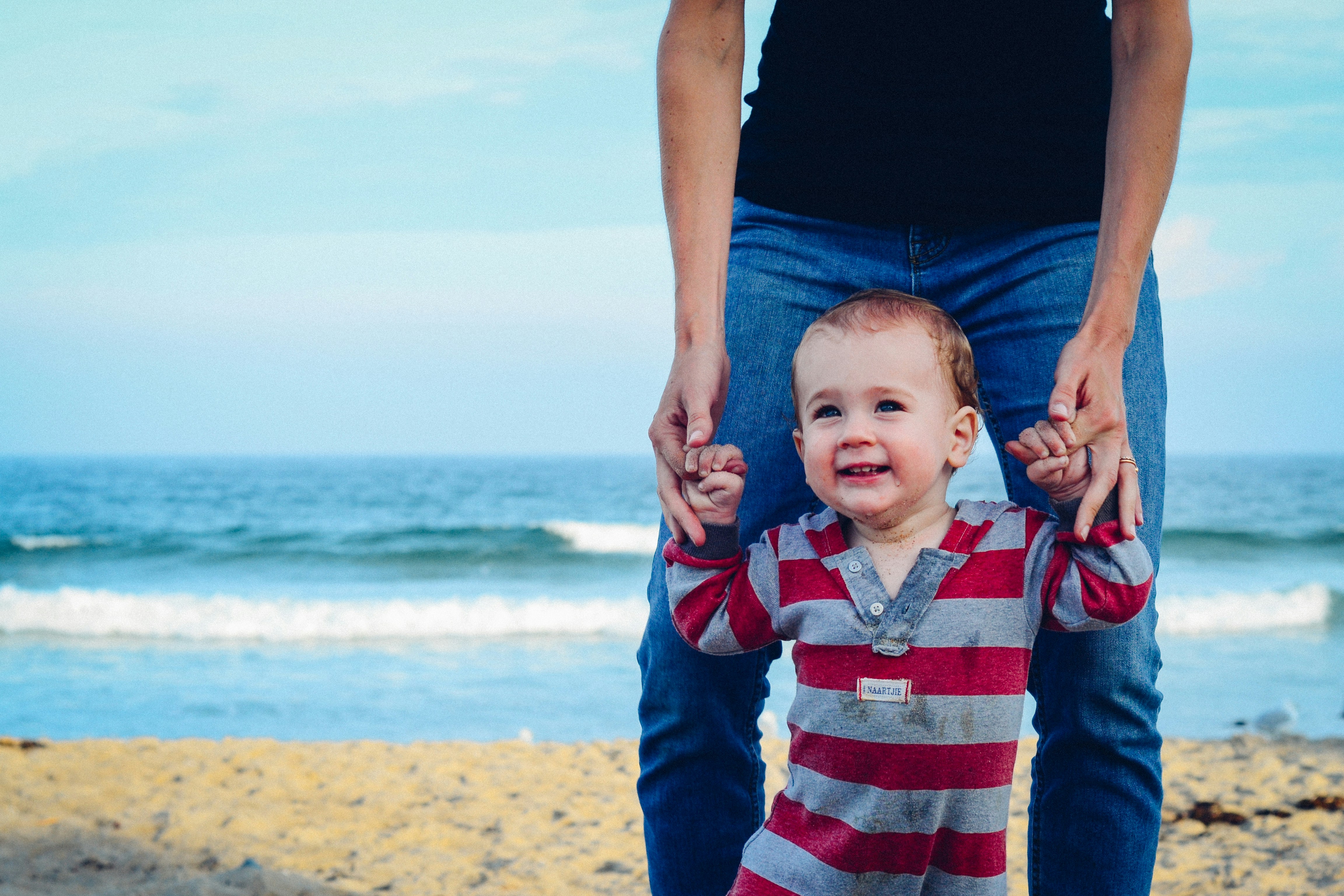 baby smiling while the father is holding his hands